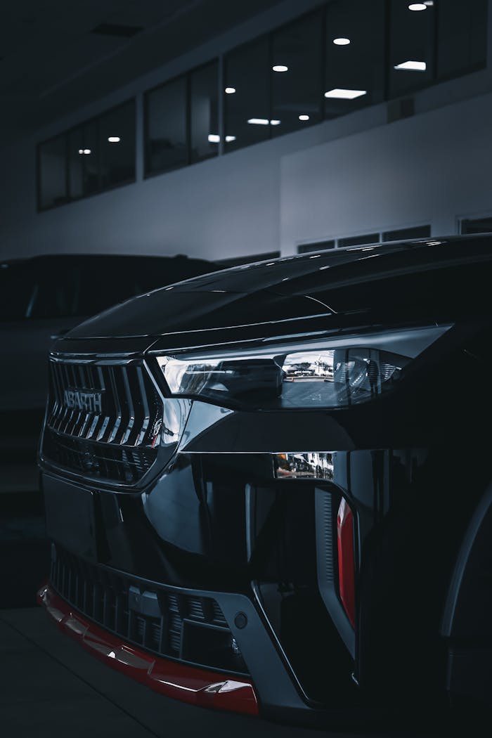 Close-up of a sleek black luxury car in an indoor showroom showcasing modern design and elegance.